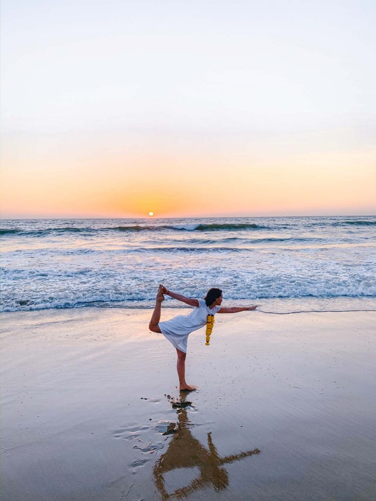 Die frischgebackene Yogalehrerin vor der untergehenden Sonne am Strand.