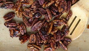 Karamellisierte Pekannüsse auf einem Backblech mit Silikonmatte und Holzspatel